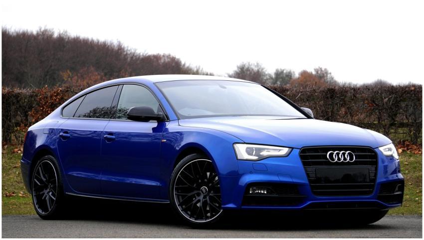 Elegant blue luxury car parked outdoors against a