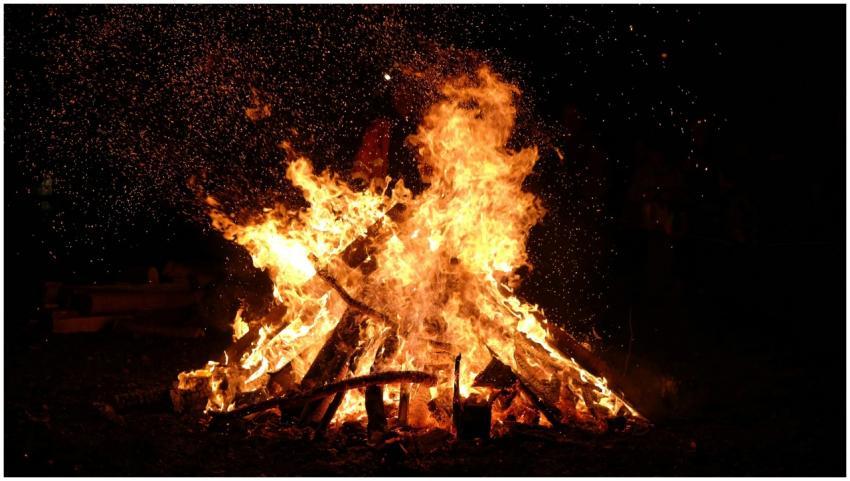 A large bonfire blazing at night with embers and s