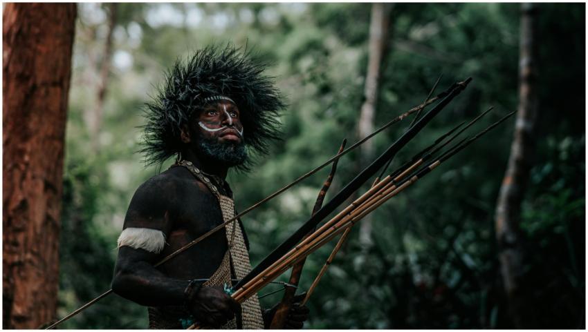 Indigenous man with traditional headdress and weap