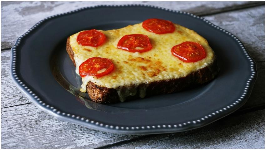 Delicious melted cheese and tomato toast on a rust