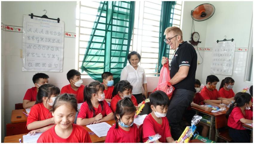 A teacher handing out gifts to students in a Vietn