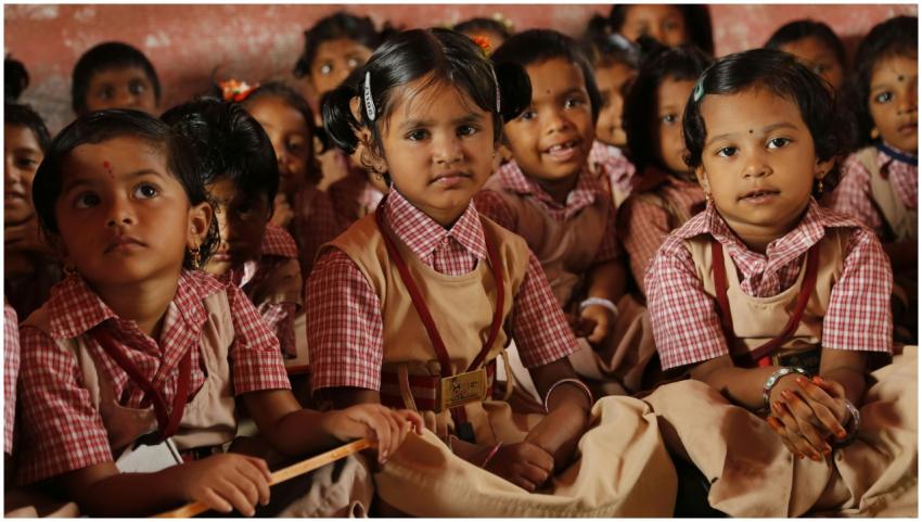 Group of young school children in uniforms sitting