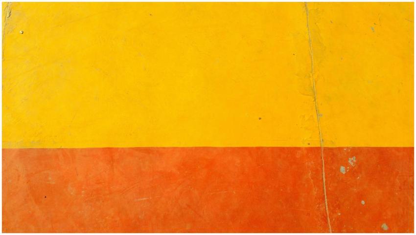Close-up of a textured yellow and orange wall with