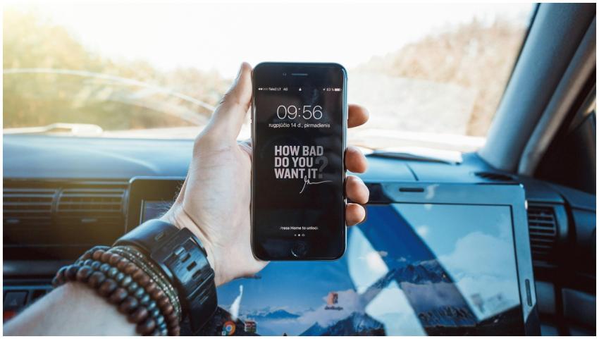 Close-up of a hand holding a smartphone in a car,