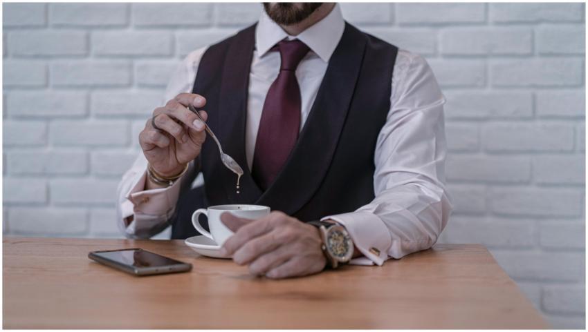 Businessman in formal attire stirring coffee at a