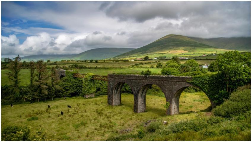 Historic viaduct amidst lush fields and mountains