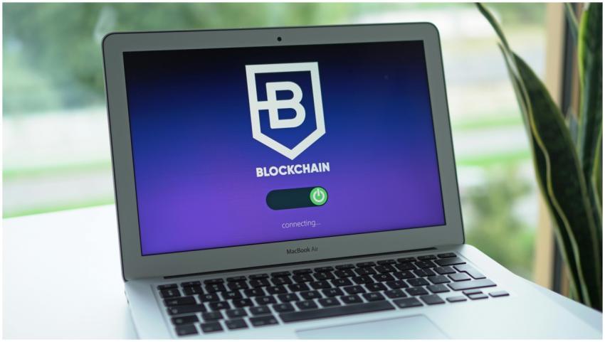 A laptop screen displays a blockchain interface, h