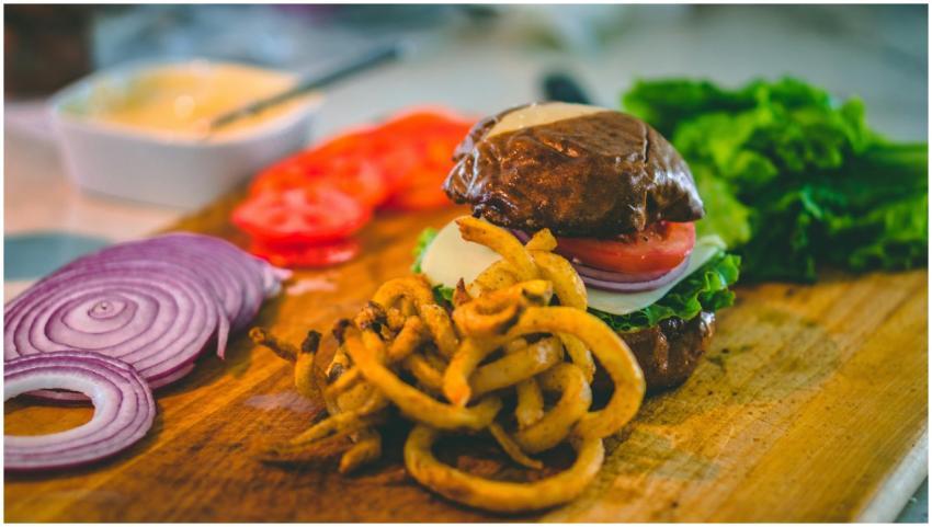 Close-up of a gourmet burger with curly fries, fre