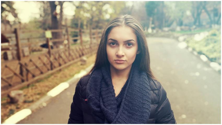 Young woman in a cozy scarf poses confidently in a