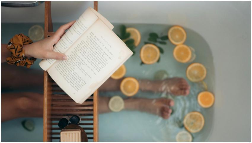 Person enjoying a citrus bath while reading a book