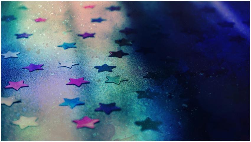 Close-up of colorful glitter stars on a vibrant bl