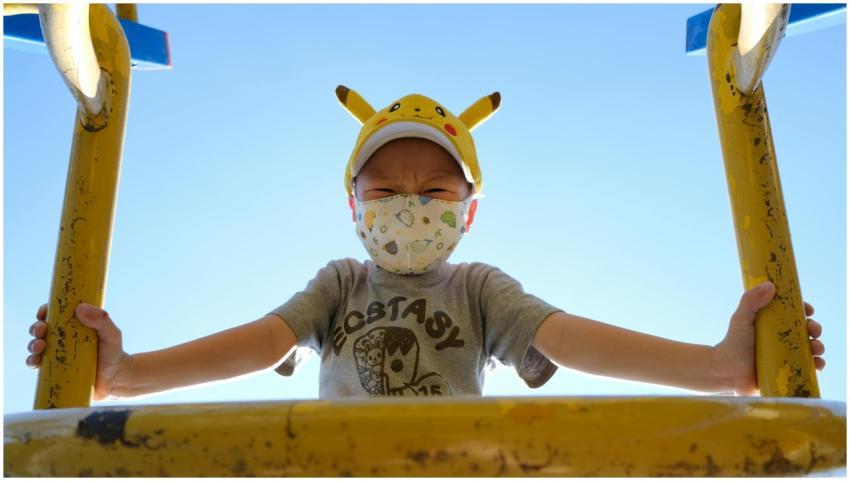 A young boy wearing a Pikachu hat and mask plays o