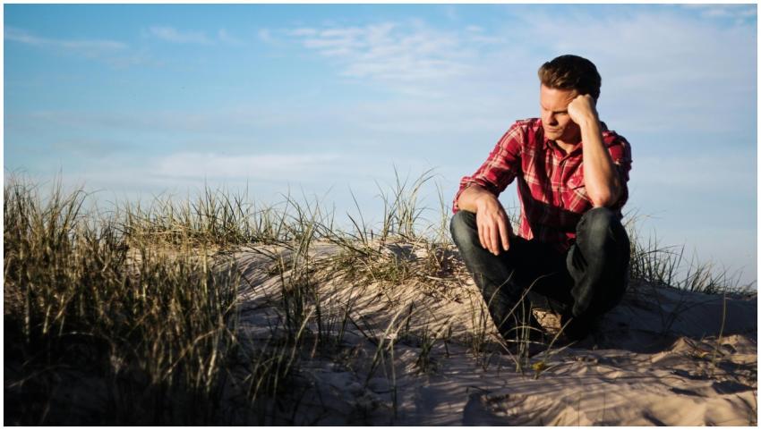Man in a red plaid shirt sitting thoughtfully on a