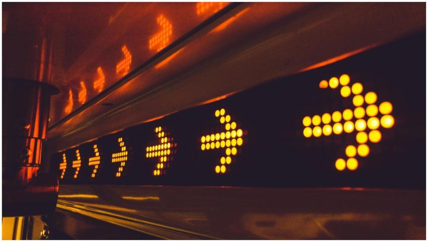 A series of glowing arrow signs in a city environm