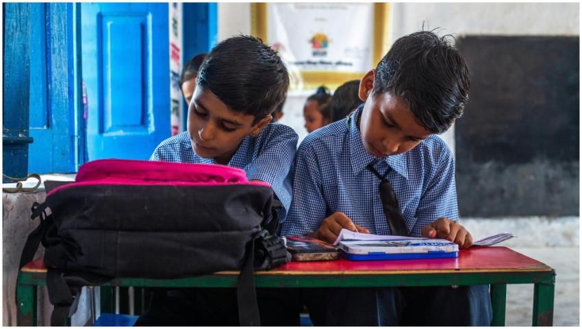 Two Indian school boys in uniforms studying in a v