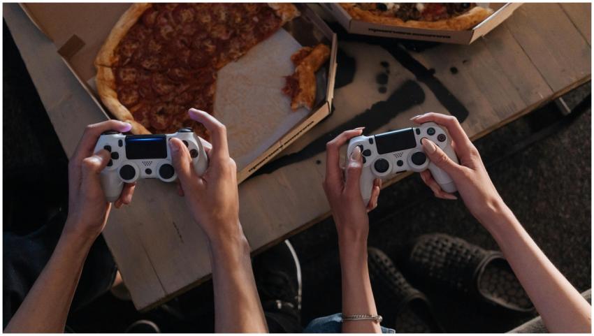 Two people enjoying a gaming session with pizza, c