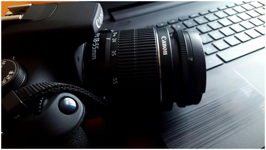 Close-up of a black DSLR camera with lens on a lap