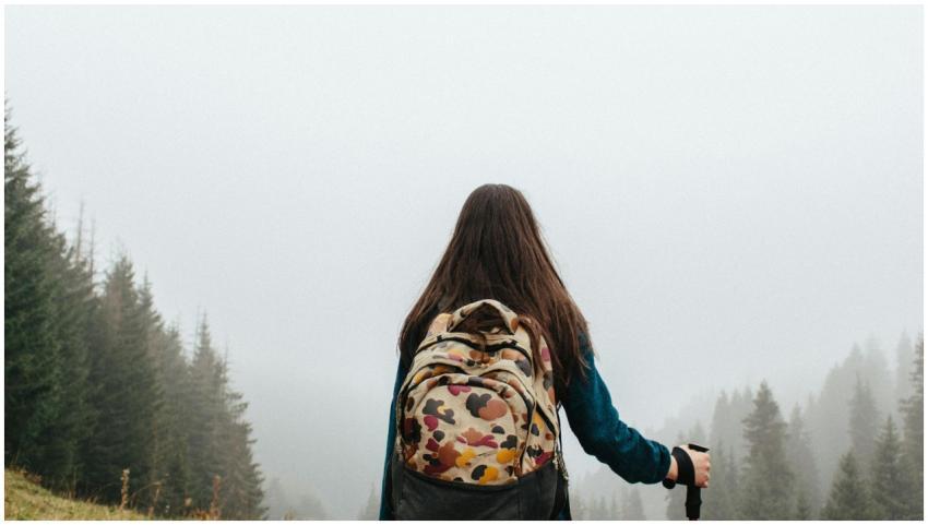 A woman hiker with a backpack explores a misty for