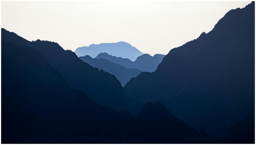 Silhouetted mountain peaks layered against a dawn