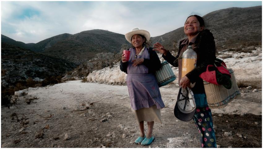 Two women share a joyful moment on a mountain road