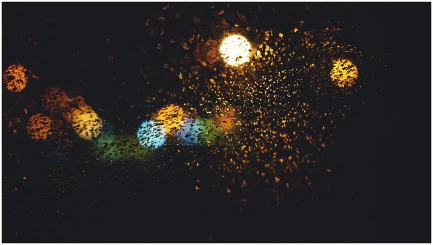 Colorful bokeh lights through a rain-dotted window