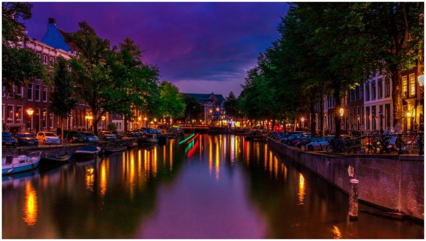 A vibrant night scene of Amsterdam's canal with co