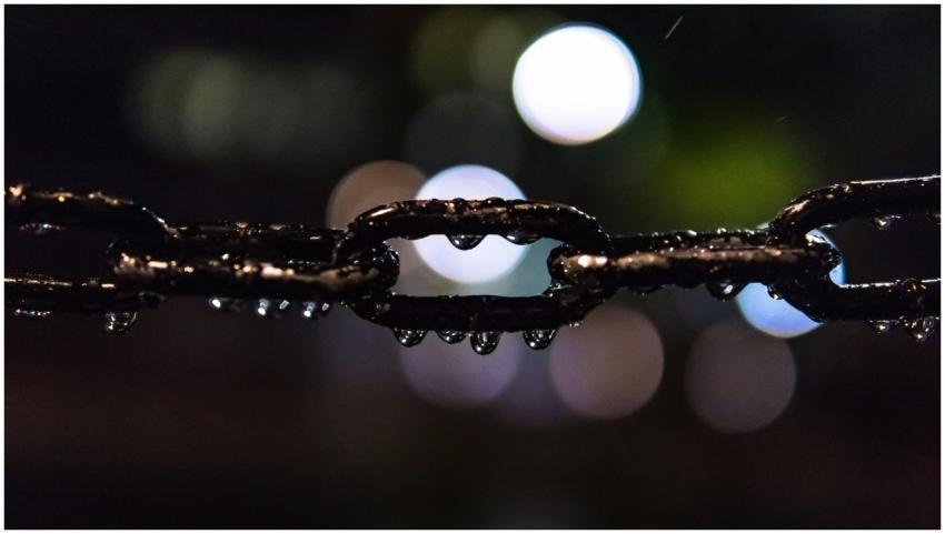 Artistic shot of a wet steel chain with bokeh ligh