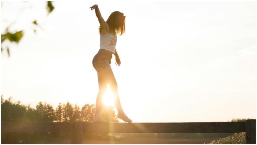 A young woman balancing on a fence during a serene