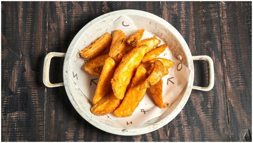 Golden crispy potato wedges served in a rustic whi