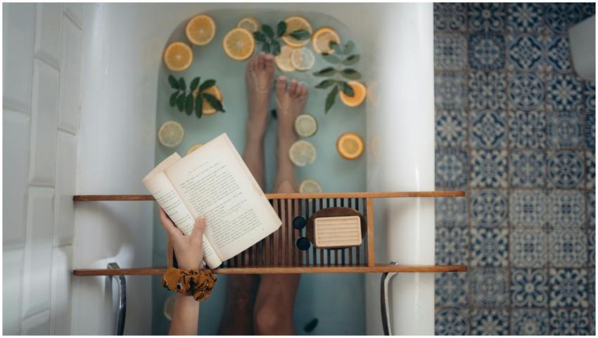 A tranquil bathtub with citrus fruits, book, and s