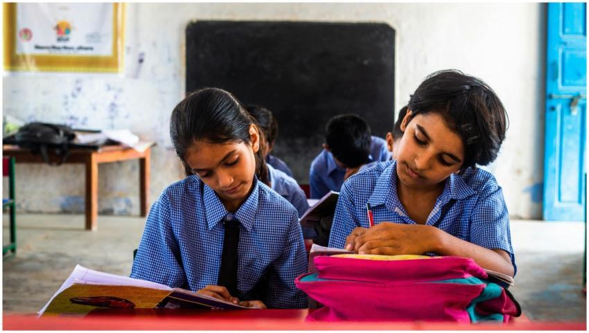 Two Indian children in school uniforms concentrati