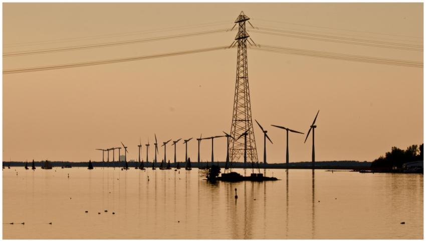 Silhouette of wind turbines and power lines over w