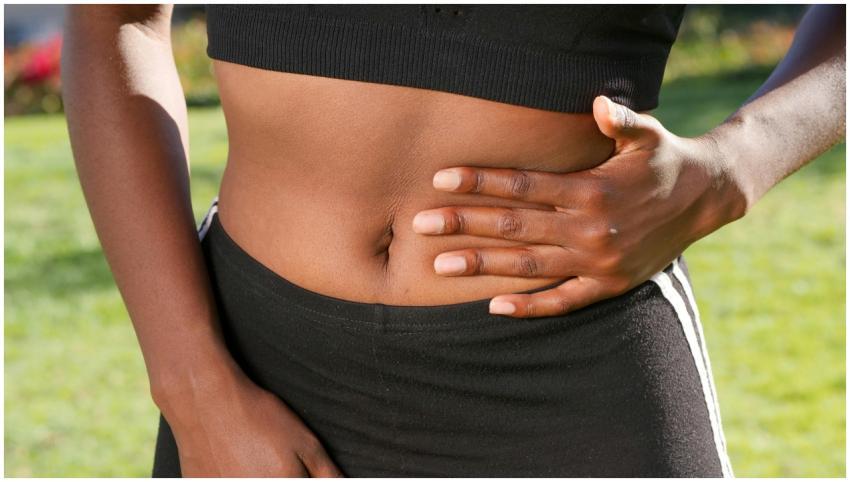 Close-up of a person holding their abdomen, indica