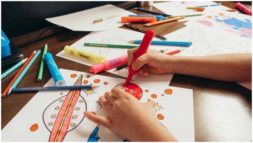 A child coloring a space-themed picture with color