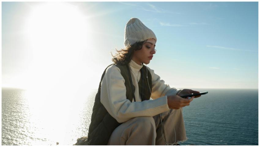 Serene moment of a woman enjoying music by the sea
