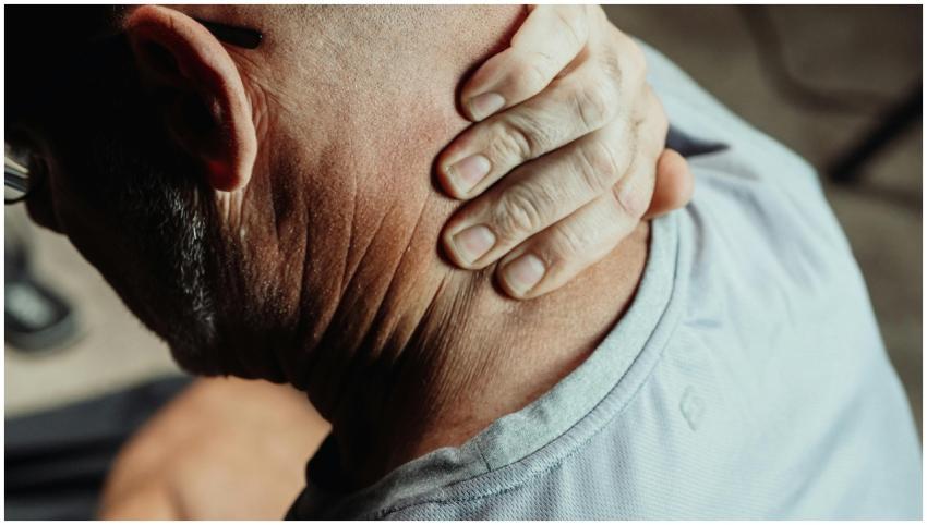 Man with neck pain holding his neck in discomfort,