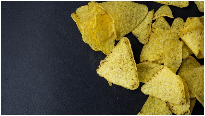 Close-up of crispy tortilla chips on a black surfa