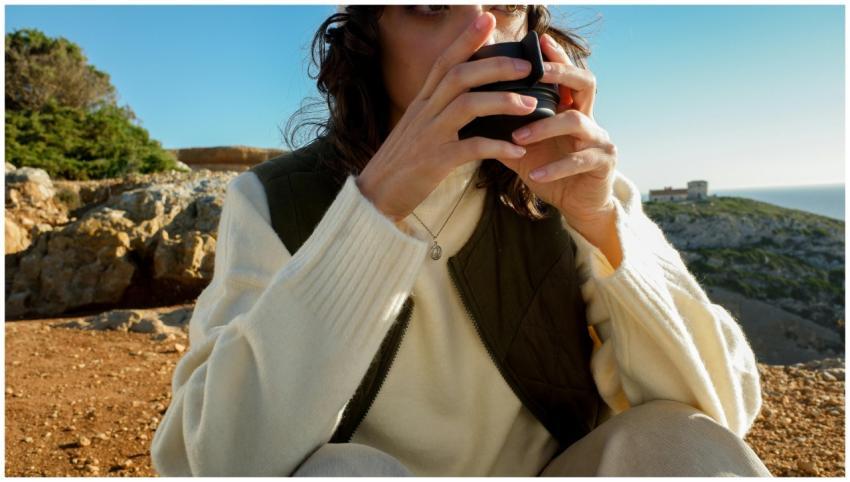Woman in a white sweater enjoys a warm beverage ou