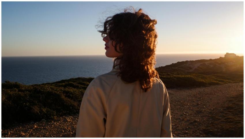 A woman with curly hair enjoys a serene ocean view