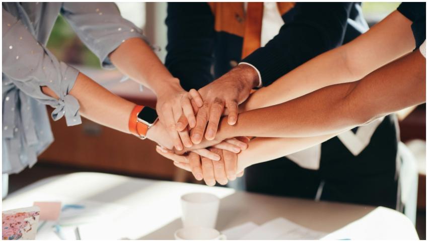 A close-up shot of diverse team members stacking h