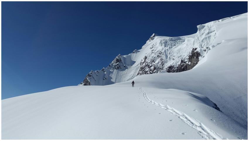 A lone mountaineer trekking through a snowy landsc