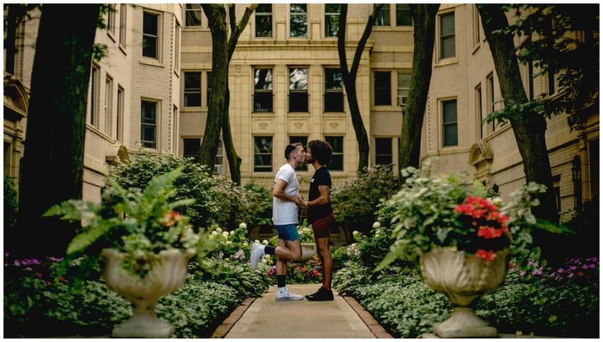 A couple shares a romantic kiss in a lush urban ga