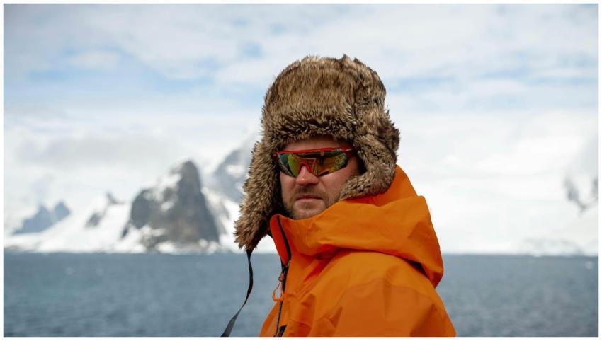 Man in orange parka and fur hat exploring Antarcti