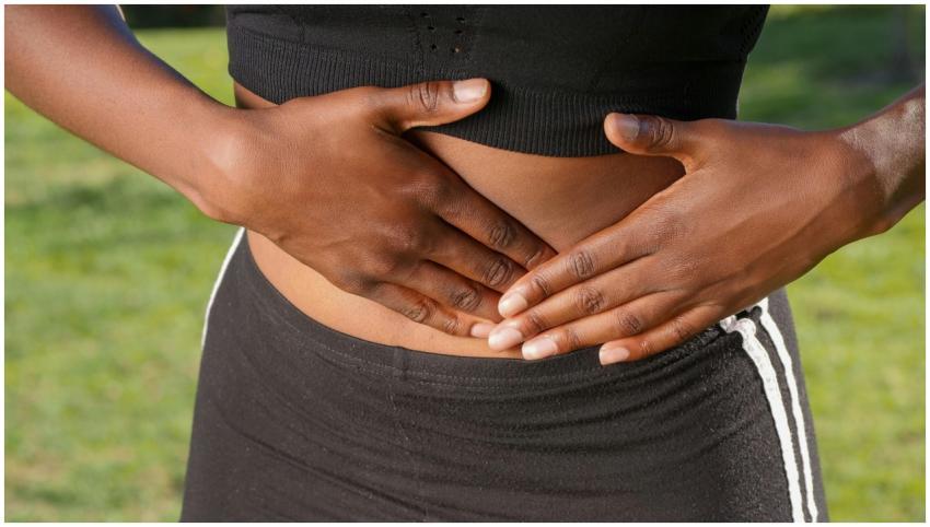 Close-up of a person holding their stomach, indica