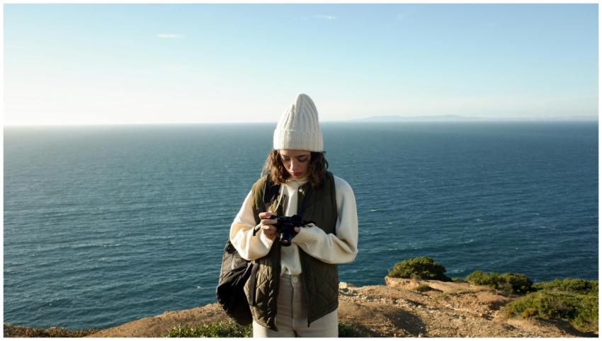 A woman in a beanie captures the stunning coastal