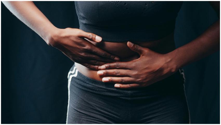 Close-up of a person pressing hands on abdomen, in