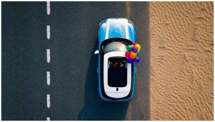 A Mini Cooper with colorful balloons drives along