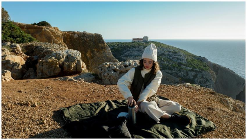 Woman in white beanie enjoying a cliffside picnic