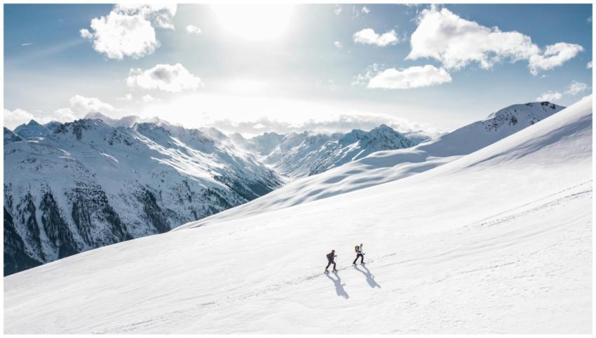 Two skiers climbing a sunlit snowy mountain slope