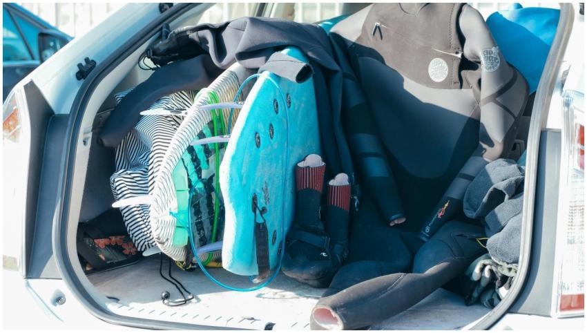 Car trunk loaded with surfboards and wetsuits, rea